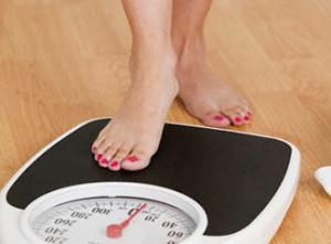 Young woman stepping on a weighing scale